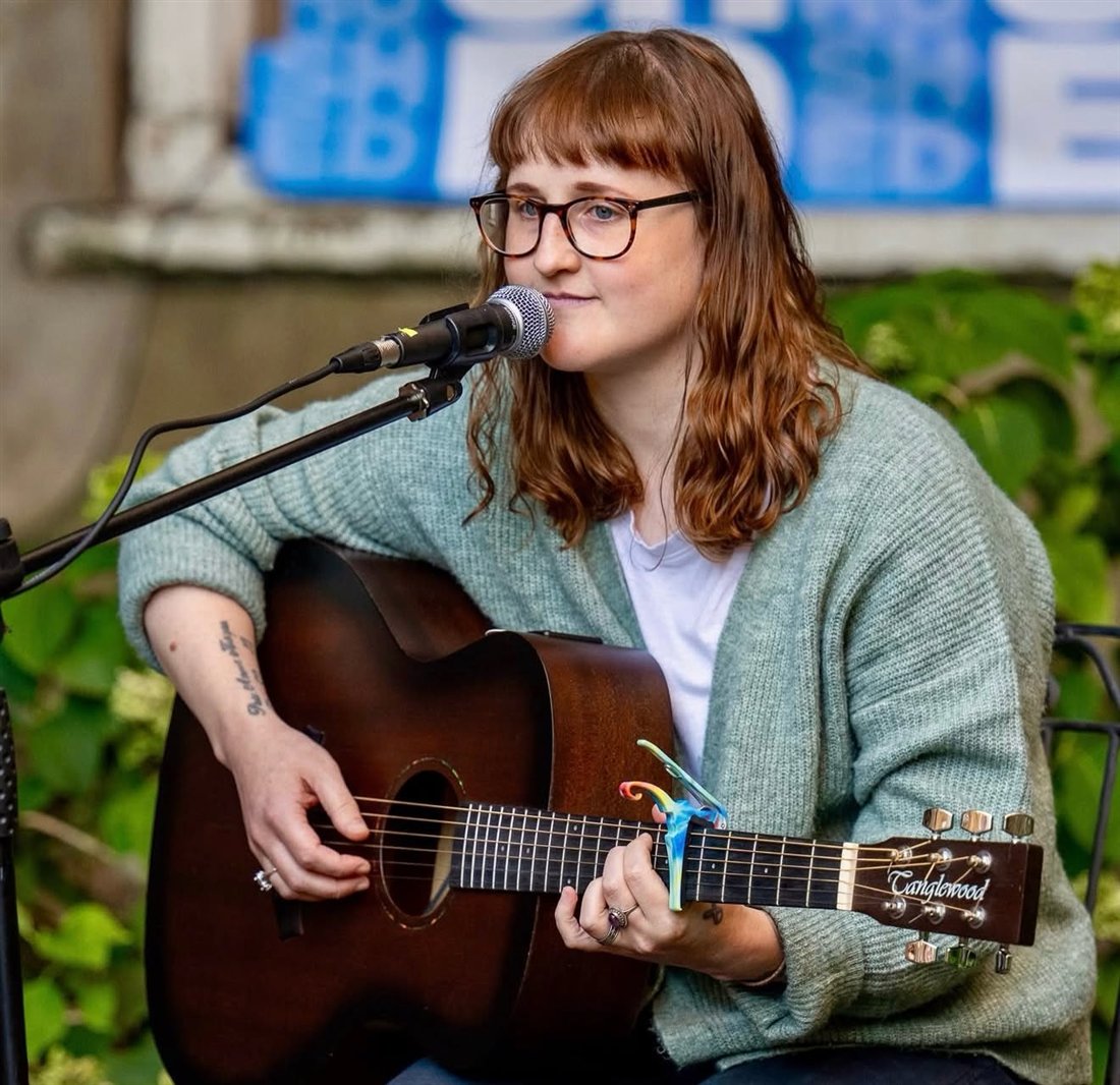 Amii Dawes playing guitar and singing